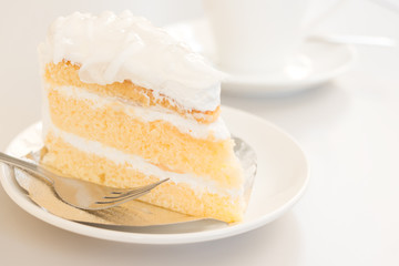 Coconut cake in white plate with coffee cup