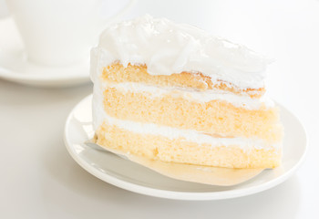 Coconut cake in white plate with coffee cup