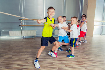 Group of kids pulling a rope in fitness room