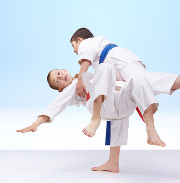 Boys are trained judo throws on a light background