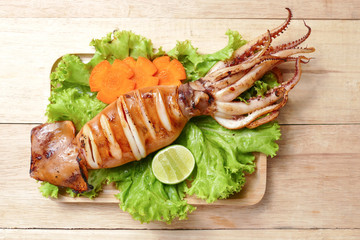 grilled squid carrot and lime on vegetable on wood plate