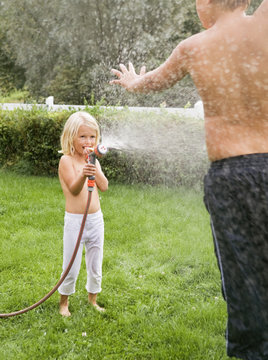 Girl spraying water on boy