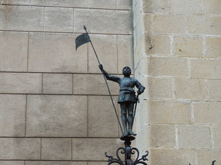 Статуя рыцаря с копьем на фоне стены старого замка 