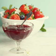 Ripe berries in colander and jam
