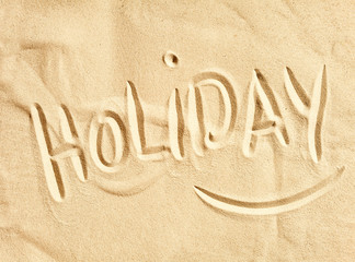 Holiday handwritten in golden beach sand