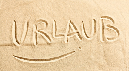 Naklejka na ściany i meble The word Urlaub written in golden beach sand