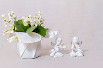 Jasmine flowers in a vase with a textile coating and figurines of angels