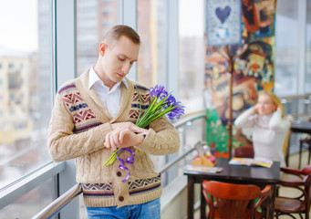 girl wants to get acquainted with a man. the guy holding flowers looks at his watch waiting for his girlfriend. Spice up relationships. Play the strangers game. 