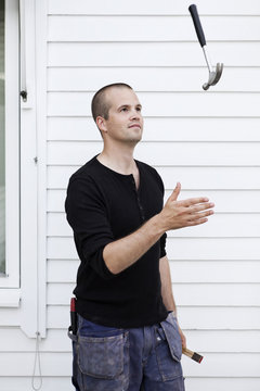 Man playing with hammer in front of house