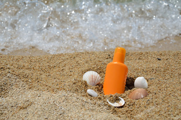 Sun lotion with sea shells on a beach with sea in background