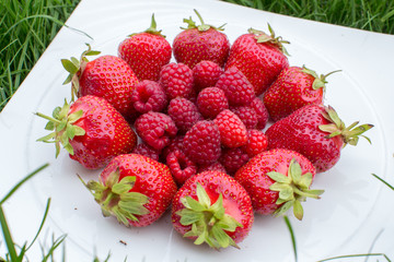 Heap of Sweet Strawberries and Juicy Raspberries Isolated on the White plate. Summer Healthy Food Concept