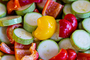 Sliced circles pickled vegetables for grilling. Courgettes, zucchini and sweet pepper with spices and oil. Selective soft focus.