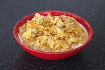 Bowl of cornflakes healthy breakfast cereal, in red bowl.