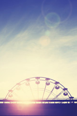 Vintage toned sunset over an amusement park with lens flare effect, space for text.
