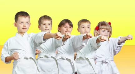 Photo sur Aluminium Arts martiaux Cinq petits athlètes frappent un bras de frappe sur fond jaune