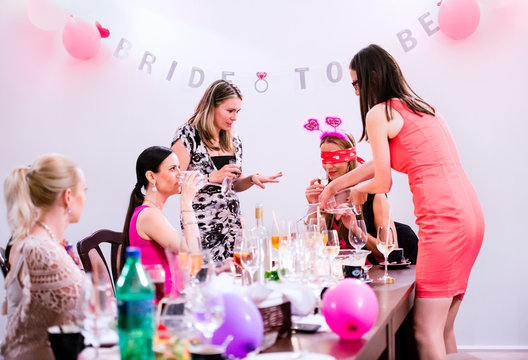 Cheerful bride and bridesmaids celebrating hen party with drinks
