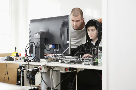 Two people helping each other by the computer
