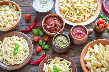 Pasta with different kinds of sauce on the wooden background