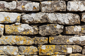 Old wall built of stones and covered with lichens, close-up