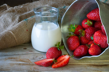 Ripe red strawberries and milk on wooden table