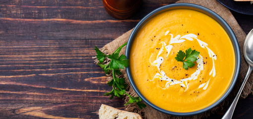 Pumpkin and carrot soup with cream and parsley on dark wooden background Top view Copy space - 113380165
