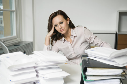 Troubled woman behind piles of envelopes