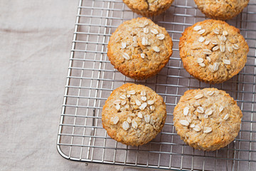 Healthy vegan oat muffins, apple and banana cakes on a cooling rack Grey textile background
