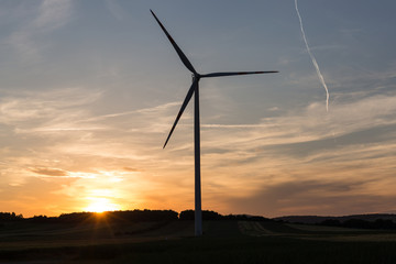 Beautiful sunset above the windmills on the field