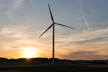 Beautiful sunset above the windmills on the field