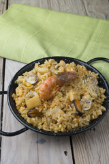 Vegetable paella with seafood on a wooden background