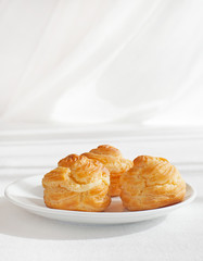 Profiteroles, choux with a custard cream, creme anglaise, whipped cream, dessert on a white plate