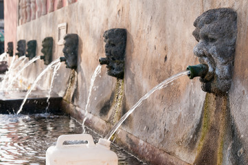 Fototapeta na wymiar Fountain with lava stone mascarons in one small village at the bottom of Mount Etna, Sicily