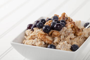 Oatmeal with chia seeds, brown sugar, blueberries, and walnuts macro shot on white wood