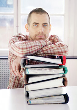 Young man and pile of folders