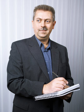 Man in a jacket making notes in a block