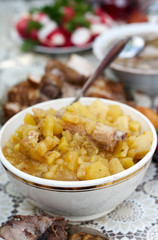 Vertical selective focus shot of an assortment of meals.Mashed Potato with pork ribs in bowl with serving spoon.Meal accompanied slice of boiled salted pork,sausage,boiled eggs,radish,fresh vegetables