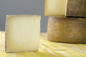 Whole wheel of sheep milk cheese over yellow wood.