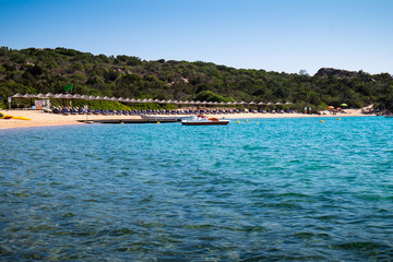 Colorful umbrellas at the beach and paradise sea in Sardinia.