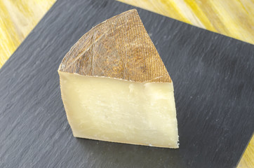 Piece of sheep milk cheese over slate plate