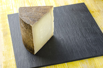 Piece of sheep milk cheese over slate plate