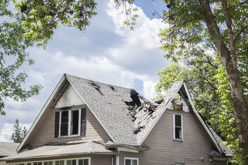 horizontal close up image of a roof of a house that has burned and fallen in under blue sky with...