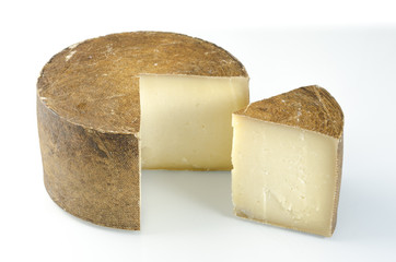 Whole wheel of sheep milk cheese over white background.