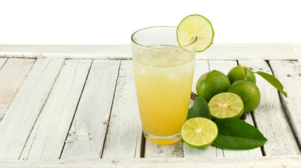 Glass of lime juice with ice on white wood