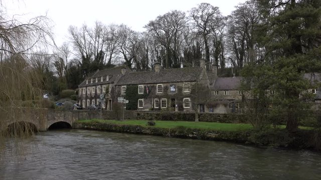 Bibury Cotswold England river and hotel pub. Historical village with homes businesses. Cotswolds, Area of Outstanding Natural Beauty (AONB) rolling hills and rivers. Destination for tourism