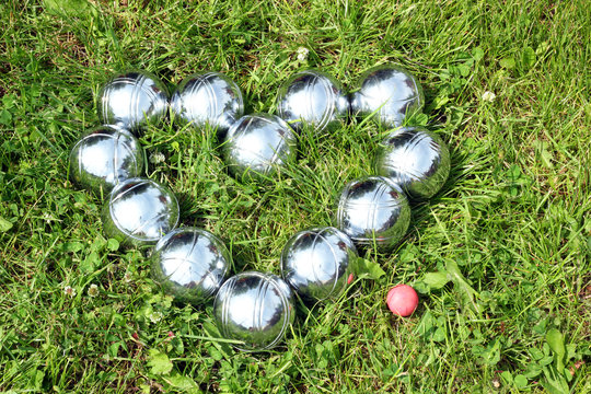 Petanque balls in the shape of a heart on the grass