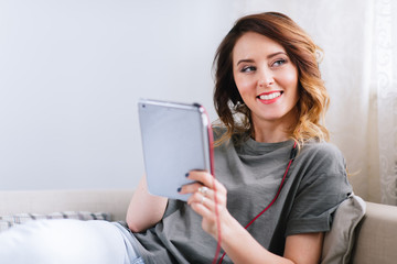 Shot of a young woman in headphones relaxing with her digital tablet at home
