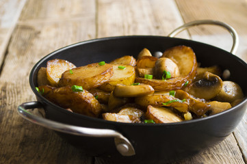 Fried potatoes with mushrooms in a frying pan