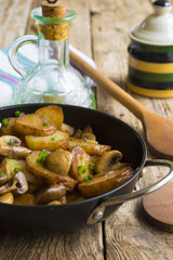 Fried potatoes with mushrooms in a frying pan