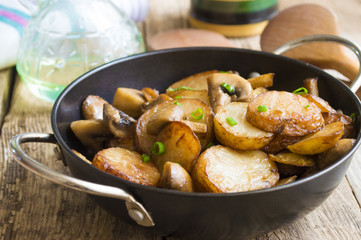 Fried potatoes with mushrooms in a frying pan