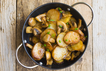 Fried potatoes with mushrooms in a frying pan